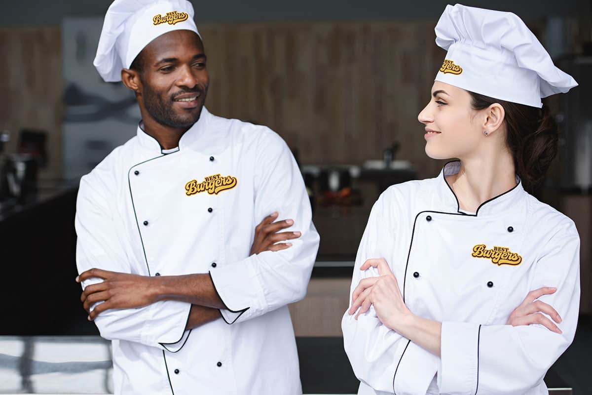 Chefs in San Antonio custom apparel smiling in a modern kitchen.